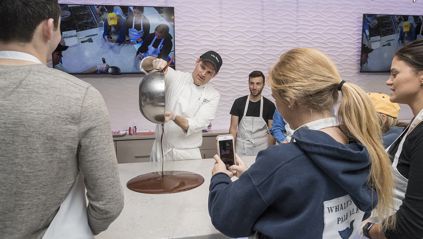 Vita Nova Executive Chef John Deflieze tempers chocolate, an essential step for making smooth, glossy chocolate, while All You Knead is Love Club President Evan Greif and fellow members look on.