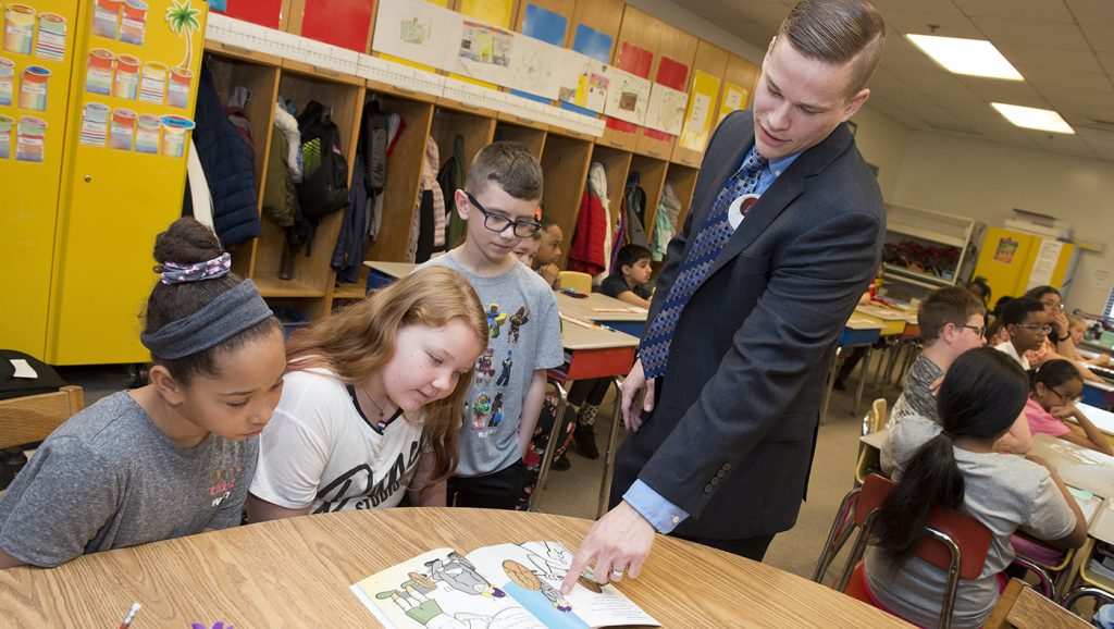 Lerner alumnus Everet Zicarelli teaches a lesson in personal finance to fourth graders Aliyah Jackson, Kayla Otto and Shane Bradley at Thurgood Marshall Elementary School for Teach Children to Save Day Week.