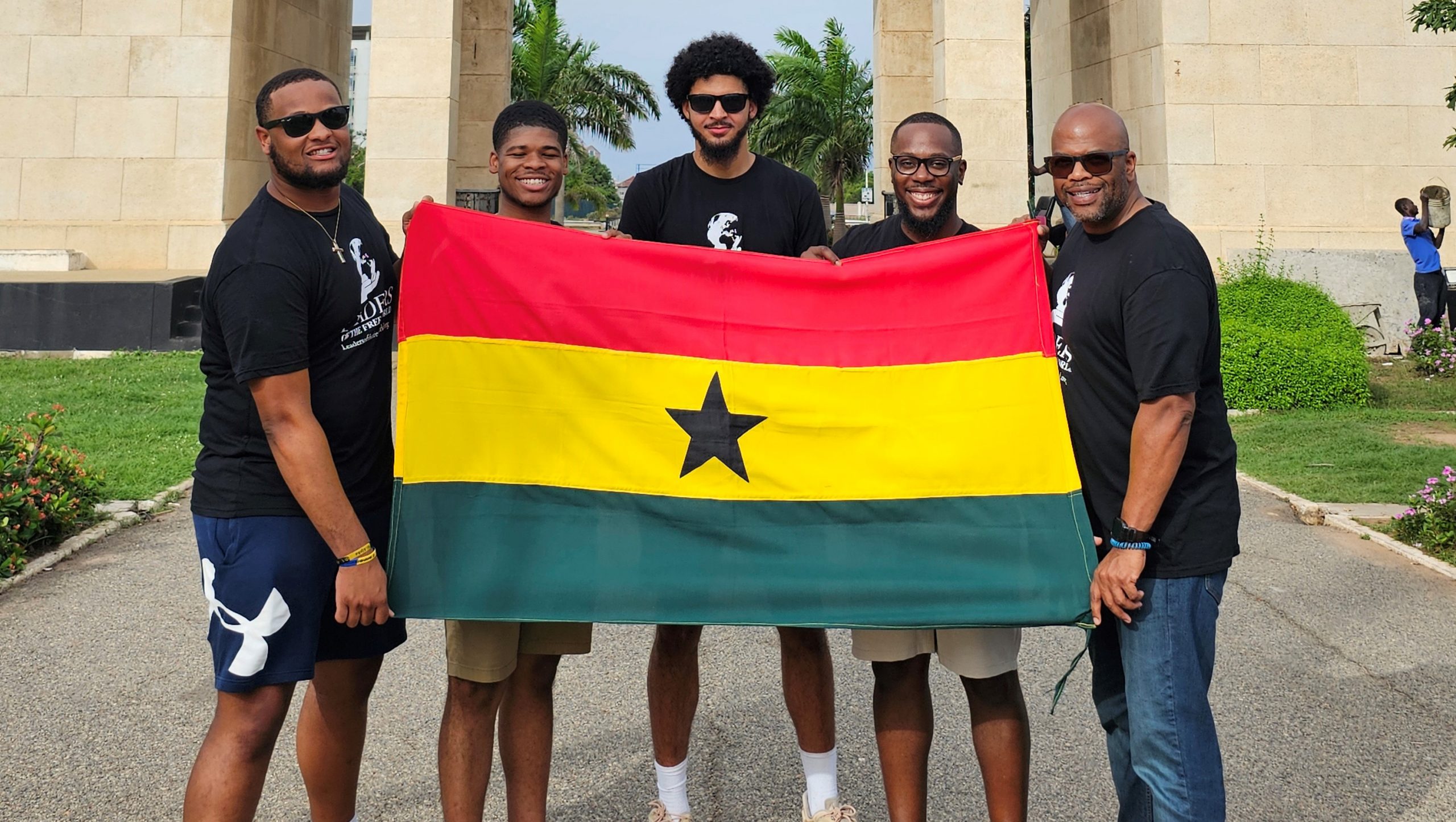 Stephen Roberts and UD students holding the Ghana flag during their trip.