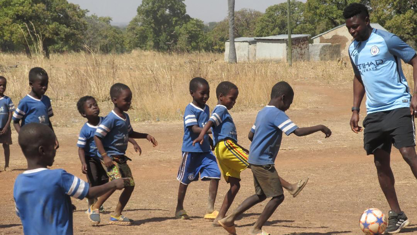 Saviour Anyagri plays soccer with Ghanaian children enrolled in his organization.