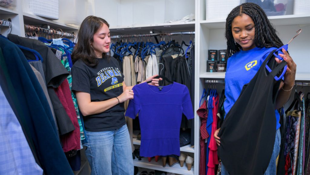 two students check out secondhand clothing pieces