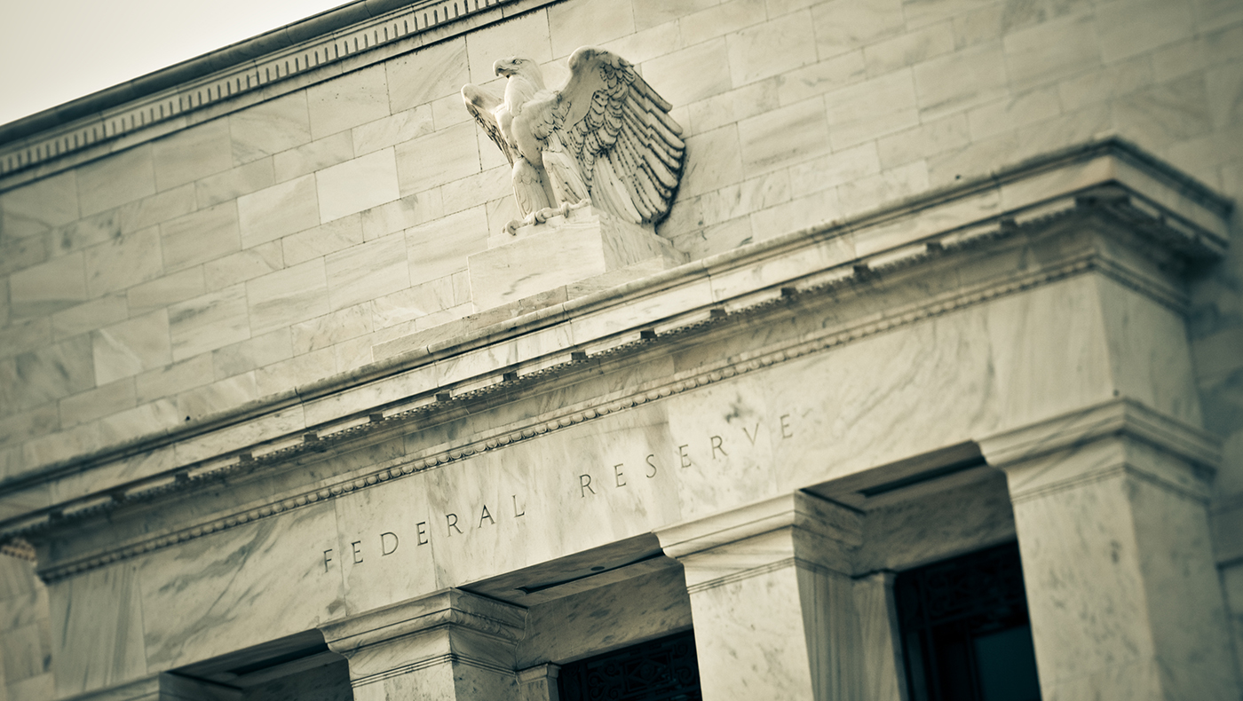 Image of a large white stone building with an eagle statue and the words Federal Reserve